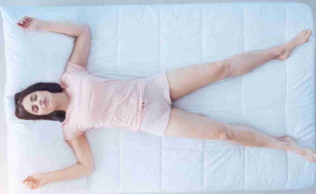 a woman sleeping in starfish position for practicing shifting technique known as the Raven method.